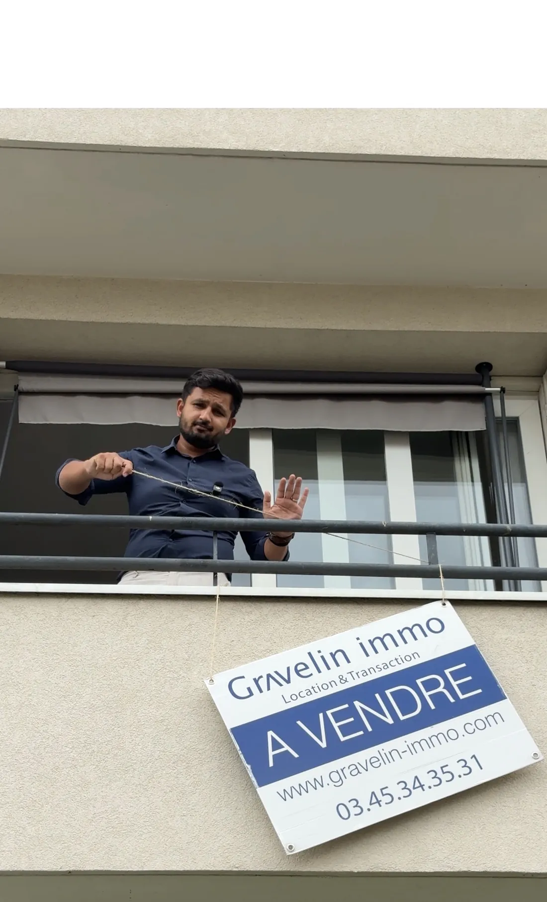 Shawez Ali accroche un panneau À vendre à un balcon